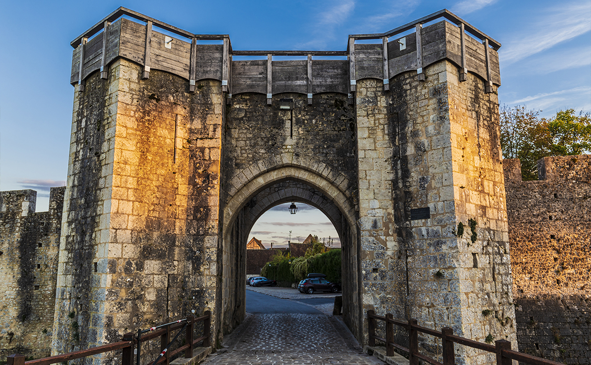 Large stone gateway with an arched entrance part of a medieval stone wall